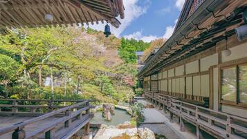 Un jardín japonés tradicional con un puente de madera, faroles de piedra y un estanque de carpas.