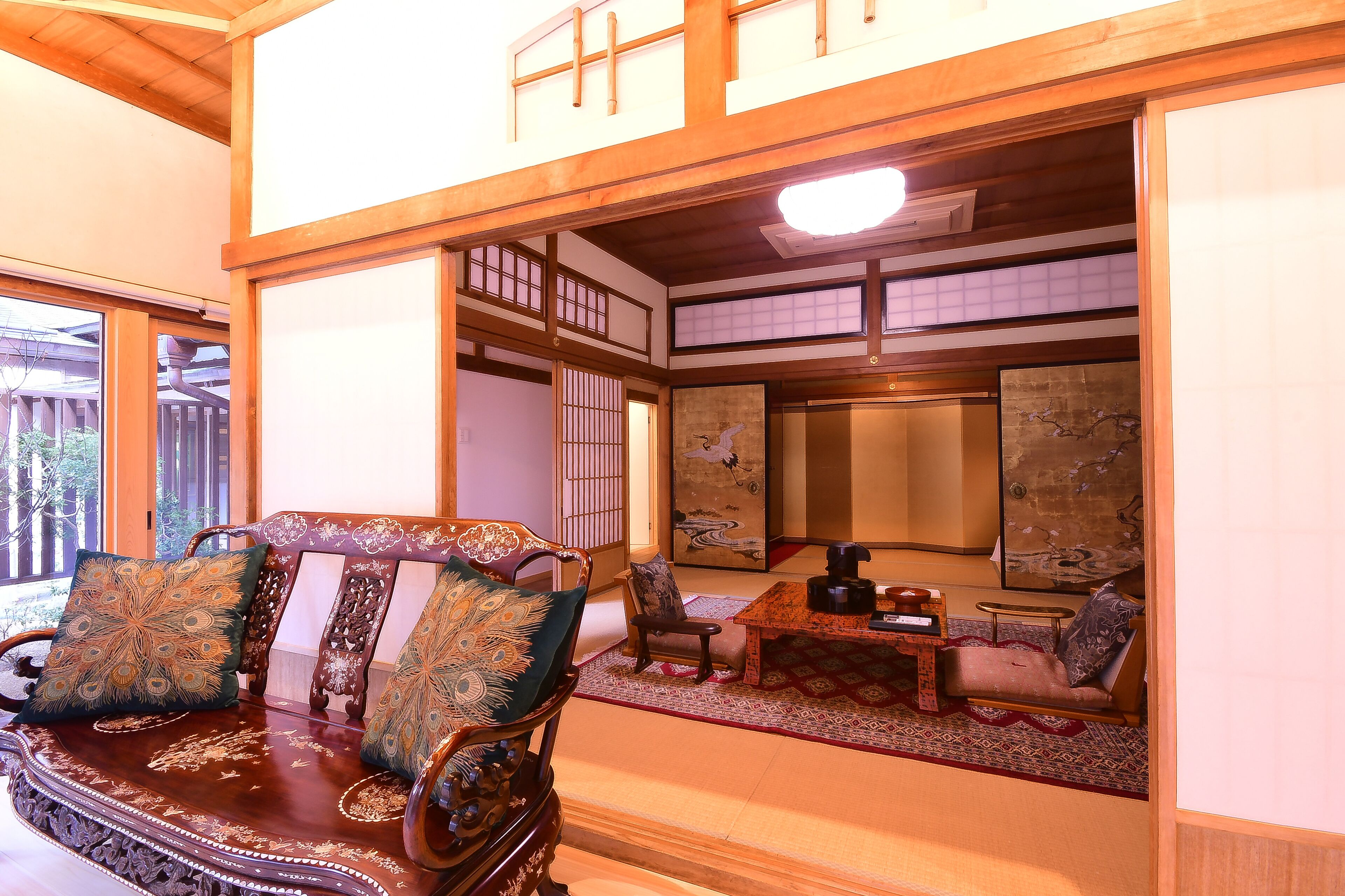 Una habitación tradicional japonesa con suelo de tatami, una mesa de madera baja y un área de asientos acolchada.