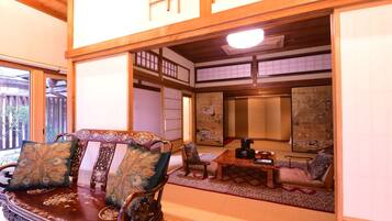 Una habitación tradicional japonesa con suelo de tatami, una mesa de madera baja y un área de asientos acolchada.