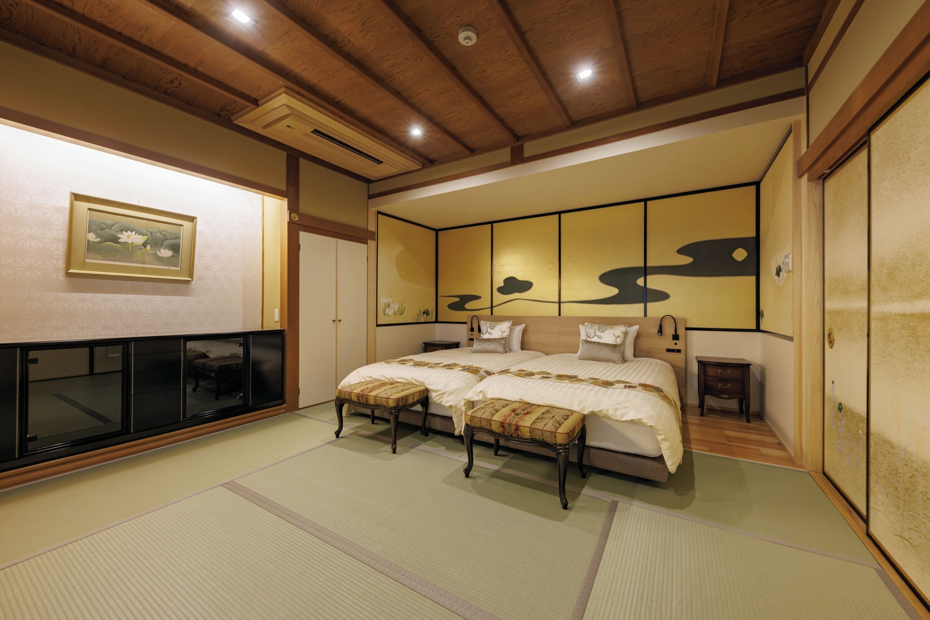 Un dormitorio de estilo japonés tradicional con suelo de tatami, una cama grande con cabecera de madera y puertas correderas.