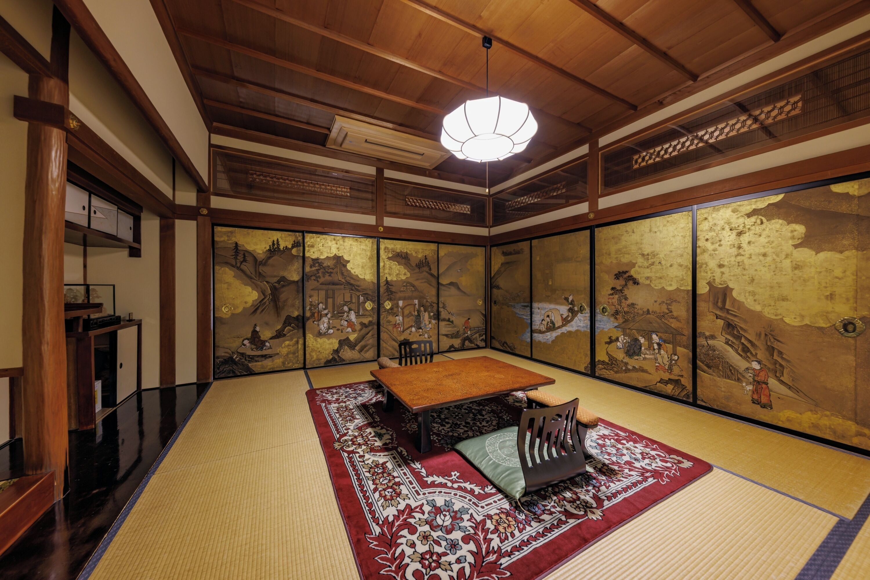 A traditional Japanese room with tatami flooring, a low wooden table, and sliding doors with artwork.