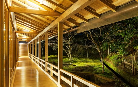 A wooden corridor with a view of a garden at night.