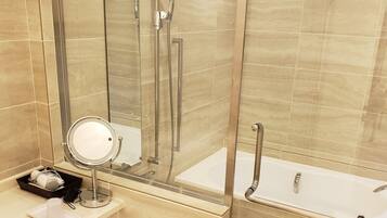 Une salle de bain dotée d’une douche à parois de verre, d’une baignoire sur pieds et d’un meuble-lavabo avec un miroir et des articles de toilette.