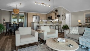 A modern living room with a sofa, armchairs, a coffee table, and a dining area with a table and chairs. - EXQUISITE BEACH HAVEN! PERFECT ROMANTIC GETAWAY! DOG FRIENDLY! (Destin)