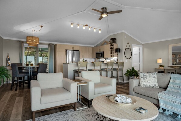 Una sala de estar moderna con un sofá, sillones, una mesa de centro y una zona de comedor con una mesa y sillas.