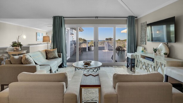A spacious living room with a large sofa, a coffee table, and a view of the outdoor patio. - EXQUISITE BEACH HAVEN! PERFECT ROMANTIC GETAWAY! DOG FRIENDLY! (Destin)