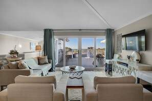 A spacious living room with a large sofa, a coffee table, and a view of the outdoor patio. - EXQUISITE BEACH HAVEN! PERFECT ROMANTIC GETAWAY! DOG FRIENDLY! (Destin)