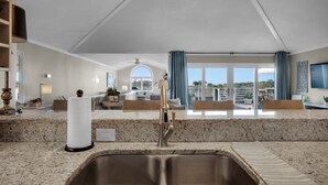 A modern kitchen with a large sink, granite countertops, and a view of the outdoors. - EXQUISITE BEACH HAVEN! PERFECT ROMANTIC GETAWAY! DOG FRIENDLY! (Destin)