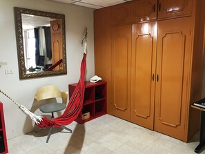 A room with a large wardrobe, a chair, a small table, and a hammock.