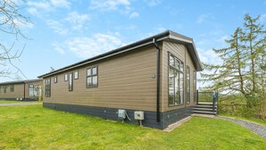 A modern single-story mobile home with a flat roof, large windows, and a small front porch.