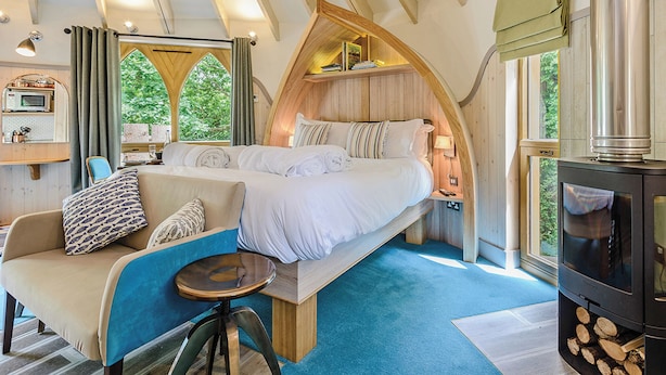 A cozy bedroom with a bed, a sofa, a small table, and a fireplace.