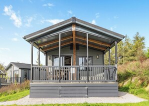 A modern building with a covered porch, large windows, and a visible door. - Dovedale Premier Lodge (Ashbourne)