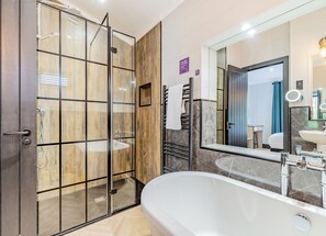 A modern bathroom with a glass shower enclosure, a freestanding bathtub, a large mirror, and a vanity with a sink. - Dovedale Premier Lodge (Ashbourne)