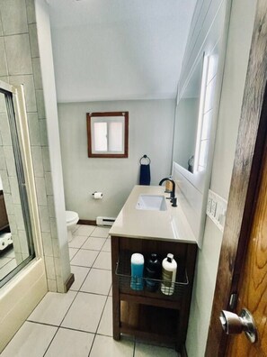 A bathroom with a shower, toilet, sink, and a mirror. - #24 *Serenity* A Lakefront Cottage Retreat (Middletown)