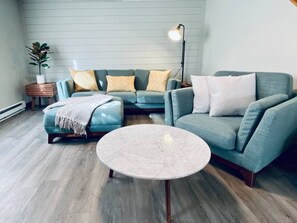 Una sala de estar con sofá, reposapiés y una mesa redonda de centro.