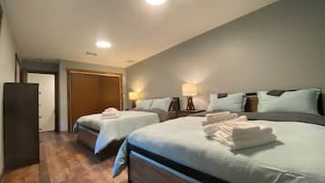 A hotel room with two beds, a wardrobe, and a door leading to another room.
