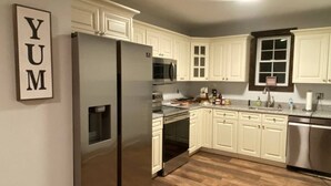 A kitchen with white cabinets, a stainless steel refrigerator, and a wooden floor. - #9 - *STUNNING*RENOVATED* *4BR HOUSE* (Southington)
