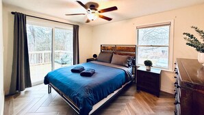 Un dormitorio con cama, ventilador de techo, mesita de noche, cómoda y ventana.