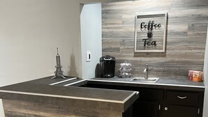 A modern kitchen with a bar area, featuring a coffee machine, a sink, and a decorative Eiffel Tower.