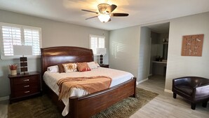 A bedroom with a wooden bed, a nightstand, a chair, and a ceiling fan.