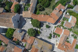 An aerial view of a residential area with closely packed houses, a central open space, and surrounding greenery. - Lovely 15th Century apartment in Osor (Osor)