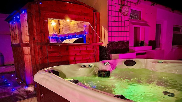 A hot tub with a wooden structure and a clock on the wall.