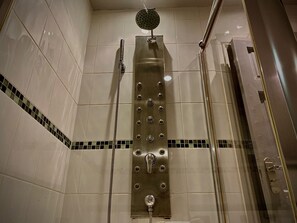 Eine Dusche mit Handbrause und fest installierter Duschköpfe, beides an einer Wand mit Fliesenmuster angebracht.