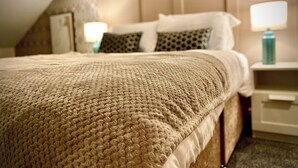 A neatly made bed with a textured blanket, a headboard with a panel design, and bedside lamps on nightstands.