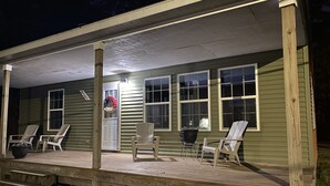 A wooden deck with four Adirondack chairs, a black pot, and a door with a wreath. - Cozy cottage home close to Lake Michigan (Muskegon)
