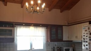 A kitchen with wooden beams, white cabinets, a central island, and a chandelier. - Immaculate 3-Bed House in Ermioni (Ermioni)