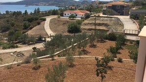 A coastal residential area with houses, a dirt path, and a view of the sea and hills. - Immaculate 3-Bed House in Ermioni (Ermioni)