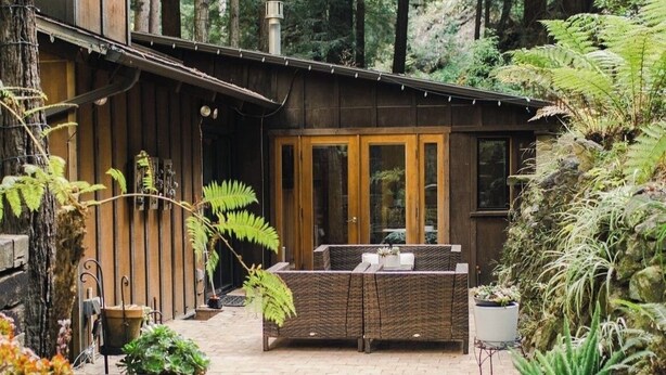 Eine moderne Holzblöcke mit einer Terrassenfläche, umgeben von dichtem Wald.