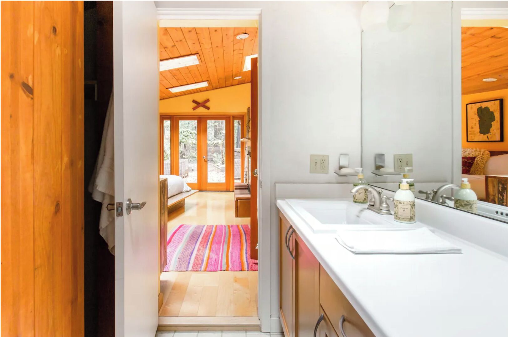 A modern bathroom with a white sink, two soap dispensers, and a mirror.