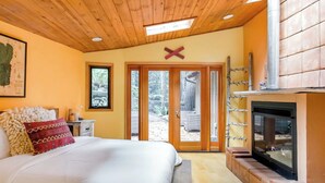 Ein Schlafzimmer mit Bett, Kamin und einer Schiebetür zu einem Außenbereich.