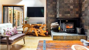 Ein gemütliches Wohnzimmer mit Kamin, Holzmöbeln und einem an der Wand montierten Fernseher.