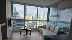 A modern living room with a sofa, a small round table, and a TV mounted on the wall. - Best Location, 2 bed, 2baths, High Speed Internet (Panamá)