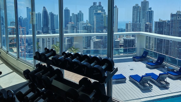 A gym with weightlifting equipment and a pool area with lounge chairs, overlooking a cityscape. - Best Location, 2 bed, 2baths, High Speed Internet (Panamá)
