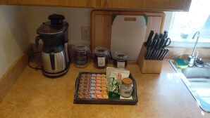 A kitchen counter with a coffee maker, jars, a knife block, and a tray of snacks. - Country Retreat in North Central FL Oasis w/ Firepit, WiFi & Nearby Springs (Old Town)