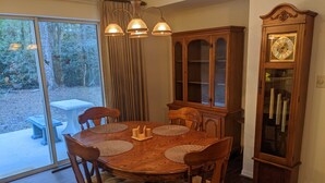 A dining area with a wooden table and chairs, a wooden cabinet, and a wall-mounted clock. - Country Retreat in North Central FL Oasis w/ Firepit, WiFi & Nearby Springs (Old Town)
