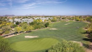 Un parcours de golf doté d’un club-house, entouré d’une végétation désertique et avec des montagnes en toile de fond.
