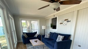 A spacious living room with a wooden floor, a blue sofa set, a coffee table, and a ceiling fan. - Lake Marion Lakehouse with 180° lake view (Elloree)