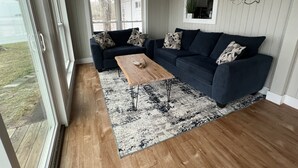 A living room with a dark blue sofa, a wooden coffee table, and a patterned rug. - Lake Marion Lakehouse with 180° lake view (Elloree)