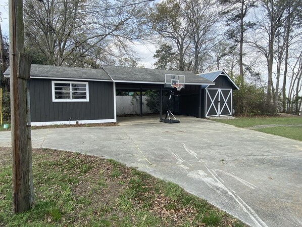 A garage with a basketball hoop, a covered driveway, and a barn.