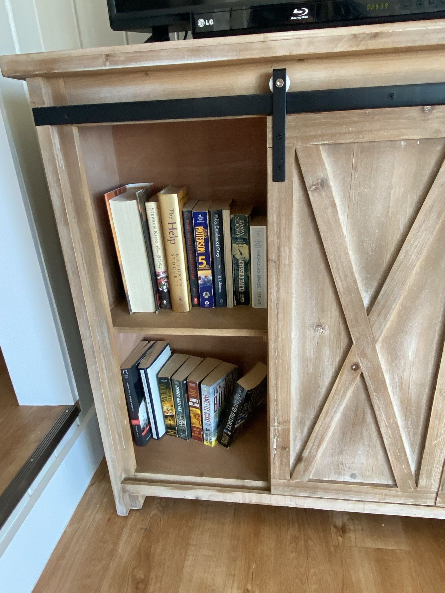 Une bibliothèque en bois dotée d’une porte coulissante, contenant divers ouvrages.