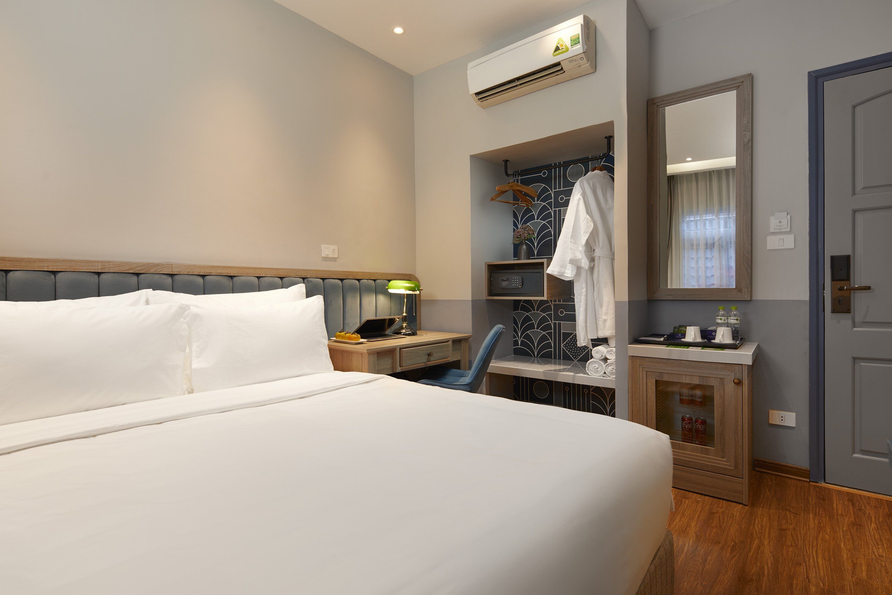 Habitación de hotel con una cama grande, un escritorio con lámpara, un espejo y un armario.