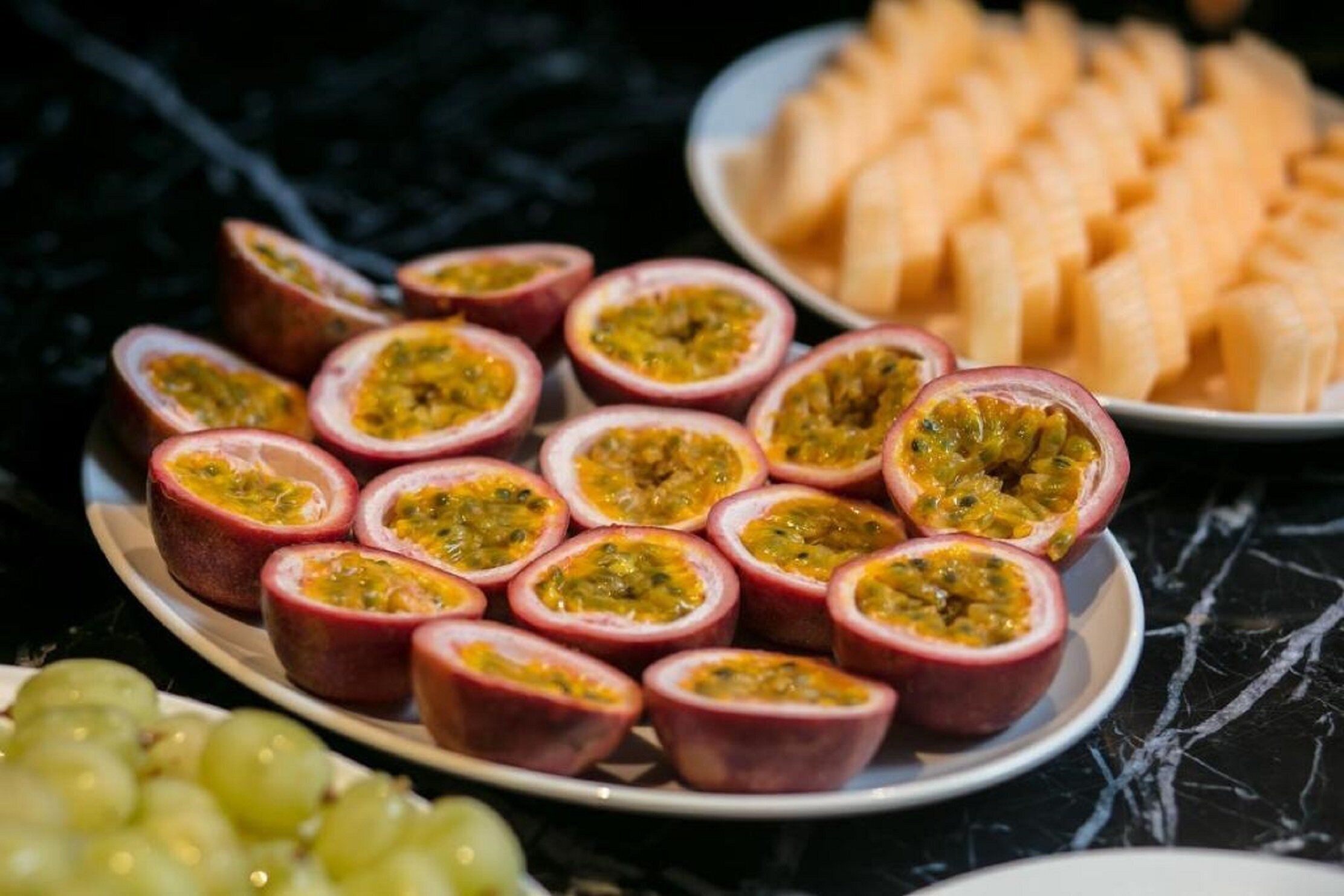 A plate of sliced passion fruit and a plate of cubed cheese.