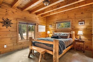 A wooden cabin bedroom with a bed, bench, bedside tables, and a window. - LOG CABIN w/Mtn View, Hot Tub, & Fireplace! (Divide)