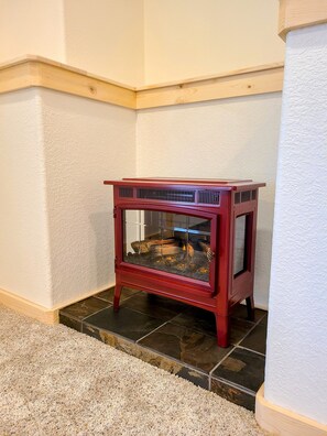 A corner fireplace with a glass door, wooden frame, and a tiled floor. - LOG CABIN w/Mtn View, Hot Tub, & Fireplace! (Divide)