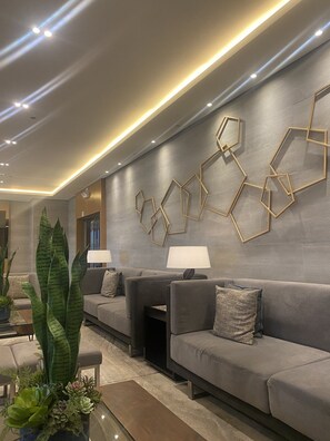A modern living room with a grey sofa set, a coffee table with plants, and geometric wall art. - 1 BR Fully Furnished Condo across MOA with Pool and Parking - S Res. Unit 0911 (Pasay)