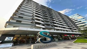 A high-rise building with a modern design, featuring multiple balconies and a prominent logo at the entrance.